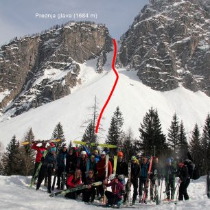 Skupinka lyžníků s nákresem výstupové a sjezdové trasy z grapy mezi dvěma vrcholy