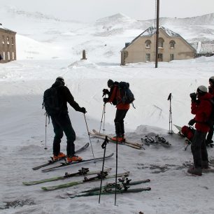 Mezi budovami u jezera Kari s výhledem na skalnatý hřeben z jižního Aragatse