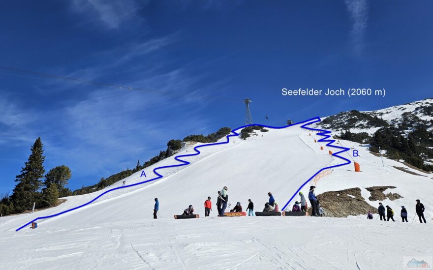 Standardní výstupová trasa vlevo od černé sjezdovky (A), alternativní výstupová trasa "freeridem" vpravo od sjezdovky (B), řada lidí chodí přímo po sjezdovce