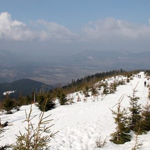 V údolích je jaro, na hřebenu spousta sněhu a částečně pod sněhem je i vrcholová část Ondřejníku na pozadí