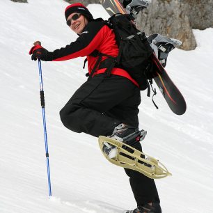 Výstup na sněžnicích se snowboardem na batohu