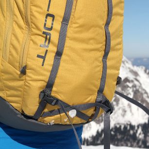 Detail nastavitelných popruhů k uchycení cepínu na čele lavinového batohu BCA Float 27 Tech