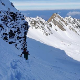 Výstup do sedla u hory Iezerul Caprei (2418 m), strmost a struktura sněhu nedovoluje pokračovat na lyžích. Je dobré je vynést pod převis a dále buď po svých do sedla, nebo s lyžemi na zádech pokračovat dál